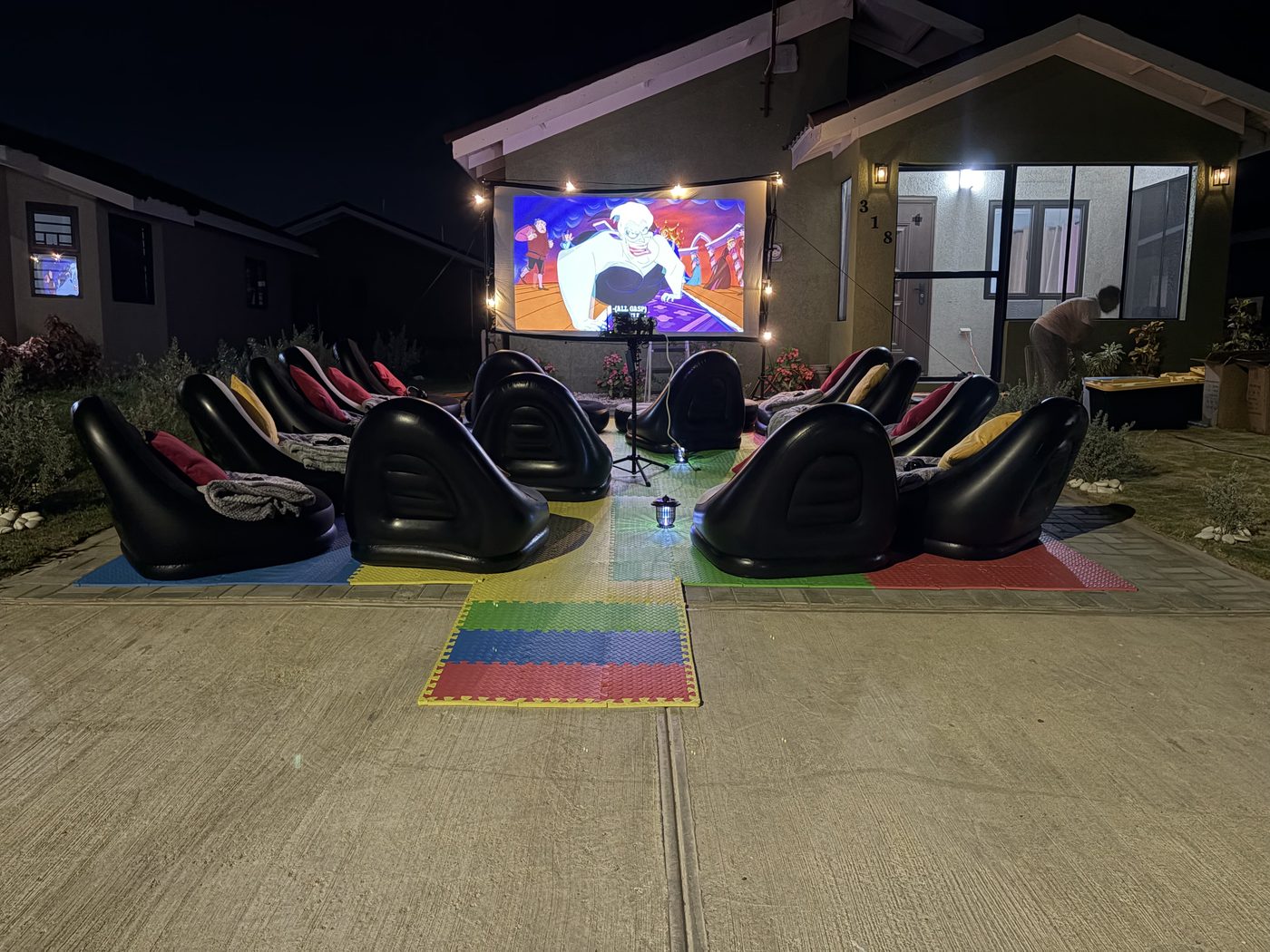 Full cinema layout at Oak Estate — chairs facing lit screen with string lights