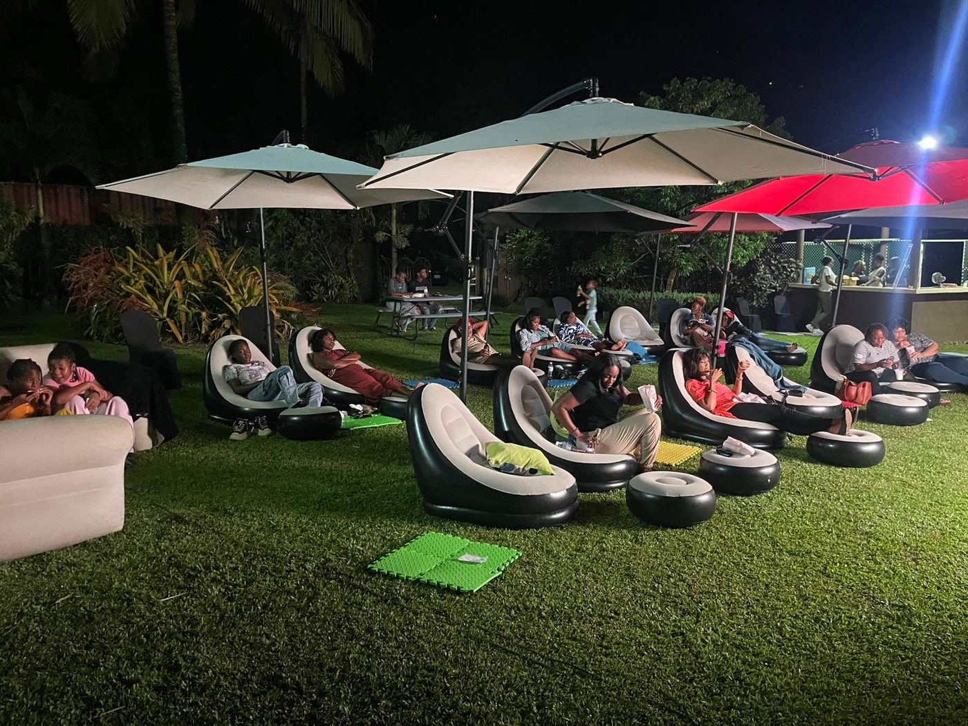 Night view at Temple Palm — guests relaxing under umbrellas at outdoor cinema