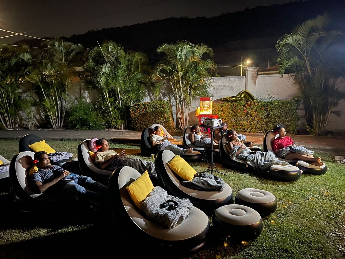 Guests watching a film on inflatable seating wearing silent cinema headphones in Jamaica
