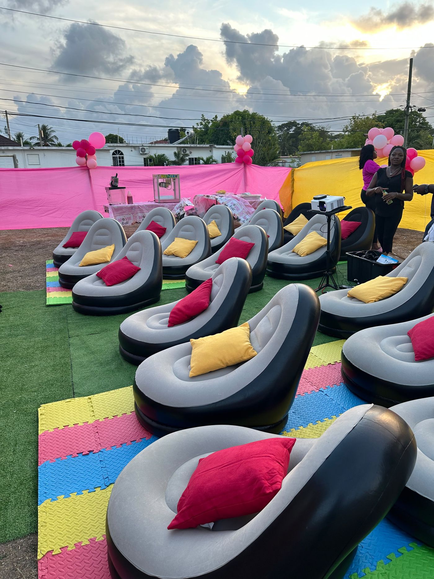 Outdoor cinema birthday setup in Jamaica with popcorn machine, balloons and inflatable seating