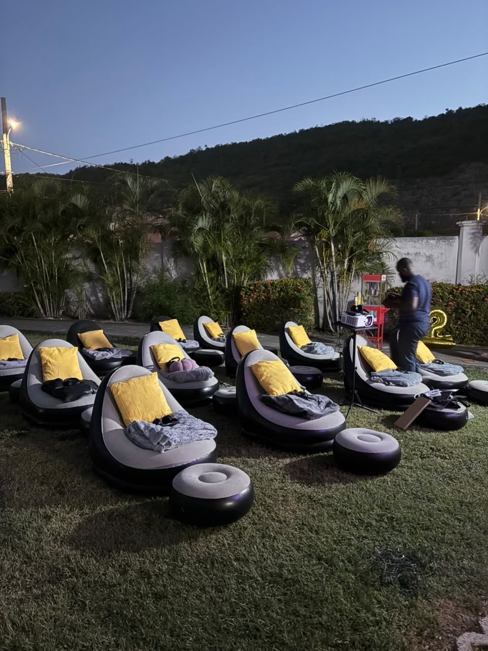 Di Nex Adventure crew setting up inflatable seating and a popcorn machine for an outdoor cinema in Jamaica