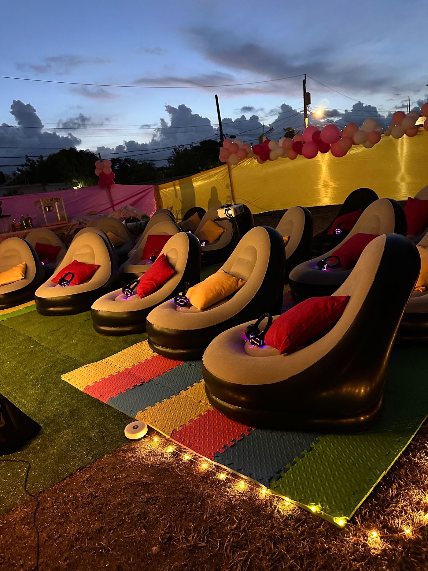 Private outdoor cinema setup in Jamaica at dusk with inflatable seating, silent headphones and decorative flooring